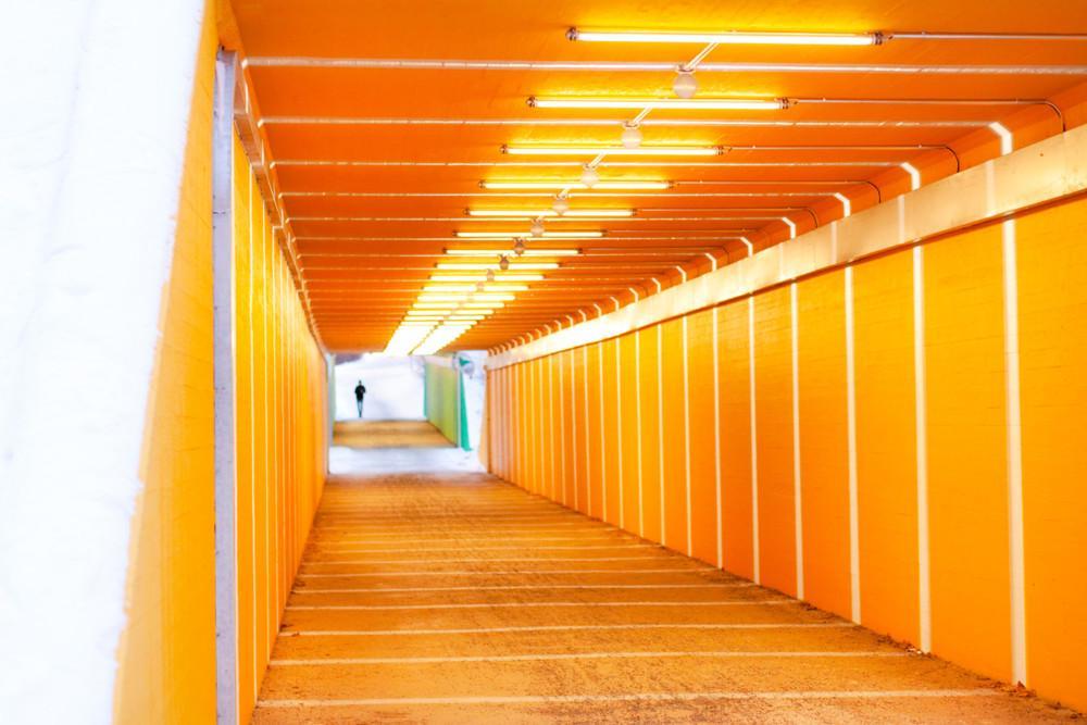 Keltaoranssiksi maalattu tunneli, jonka seiniä ja kattoa kiertää kauttaaltaan valot.